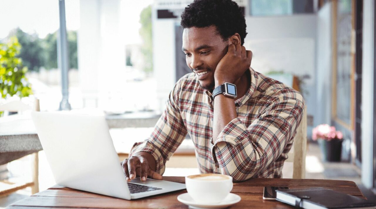 young african-american man working on computer and reading about the difference between email vs. direct mail