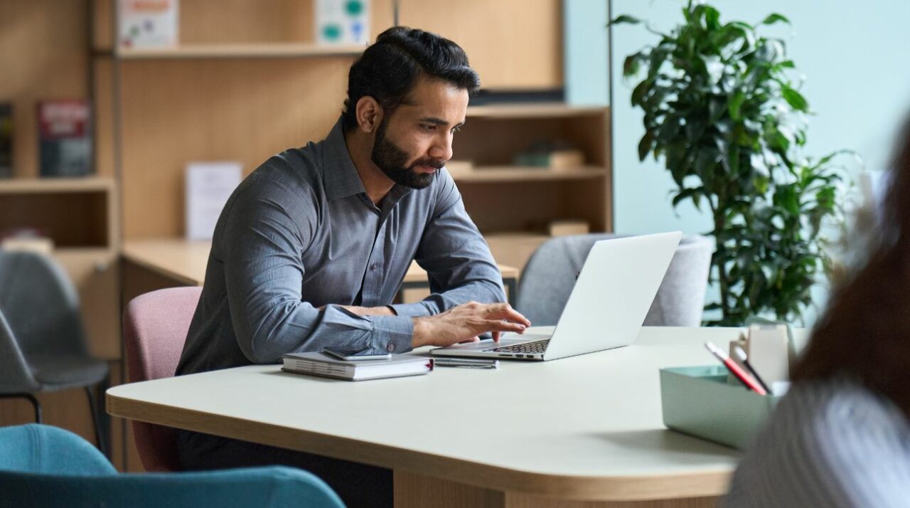 caucasian man working on computer and reading about the aida model in marketing