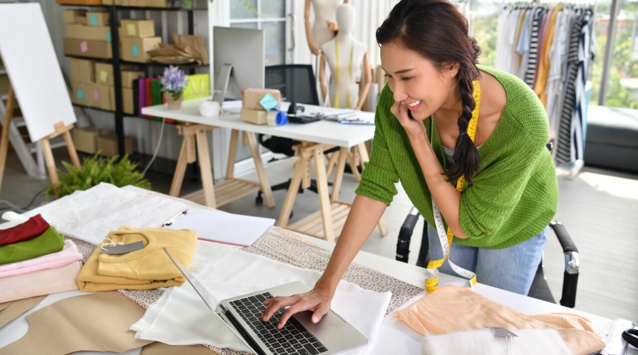 young female entrepreneur checking laptop and smiling