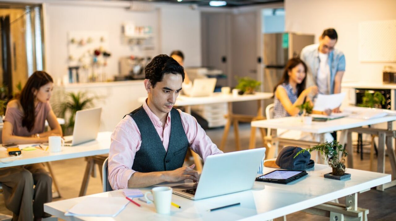 Man uses an email finder tool in his modern office among all of his colleagues.