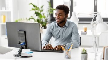 young African-American man smiling and working on computer to learn how to clean your email list