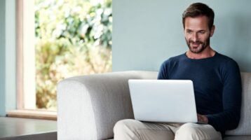 man sitting on couch working on computer to set up email authentication for microsoft