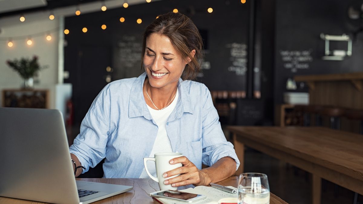 Woman sits in front of laptop with coffee mug in hand, thankful that she asked for this coffee chat.