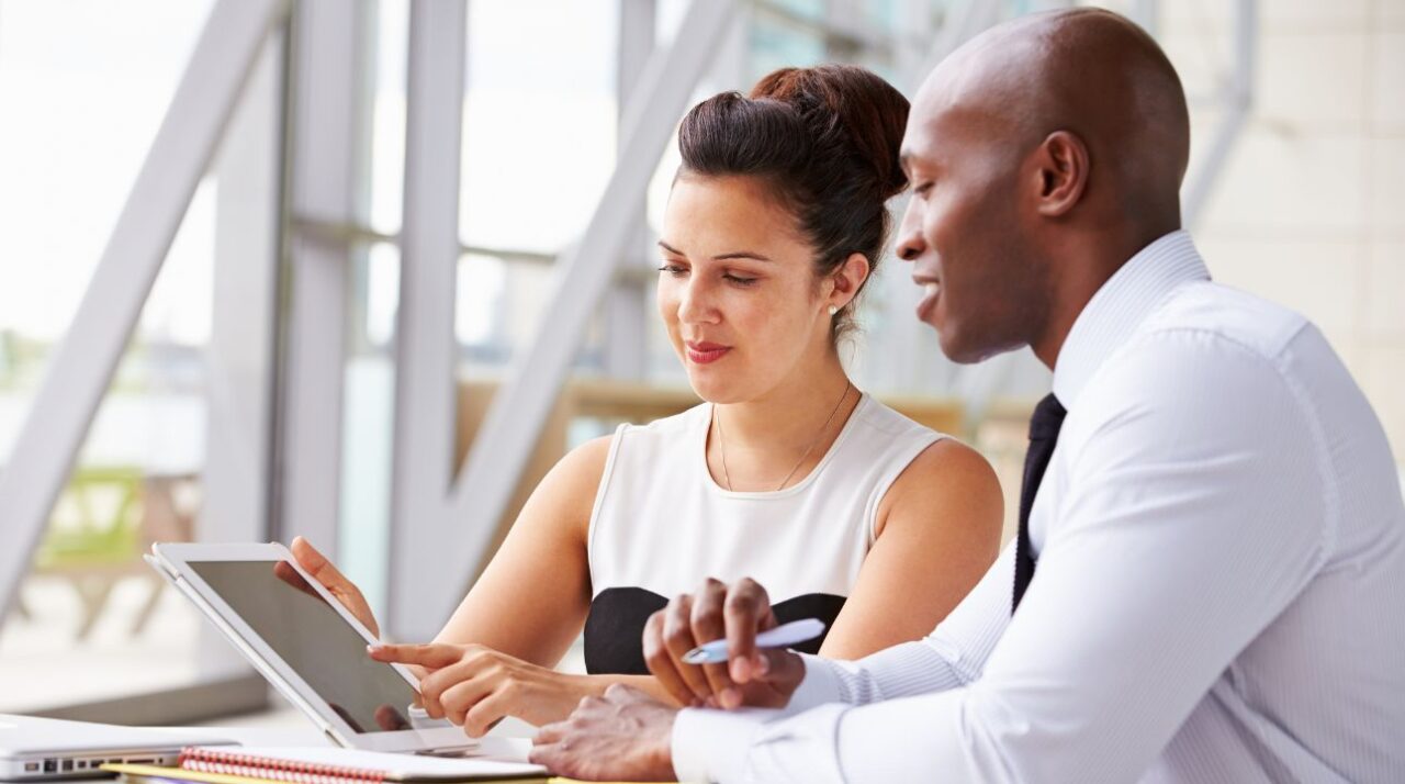 man and woman working together on tablet to understand how to avoid the spam folder when sending email marketing campaigns