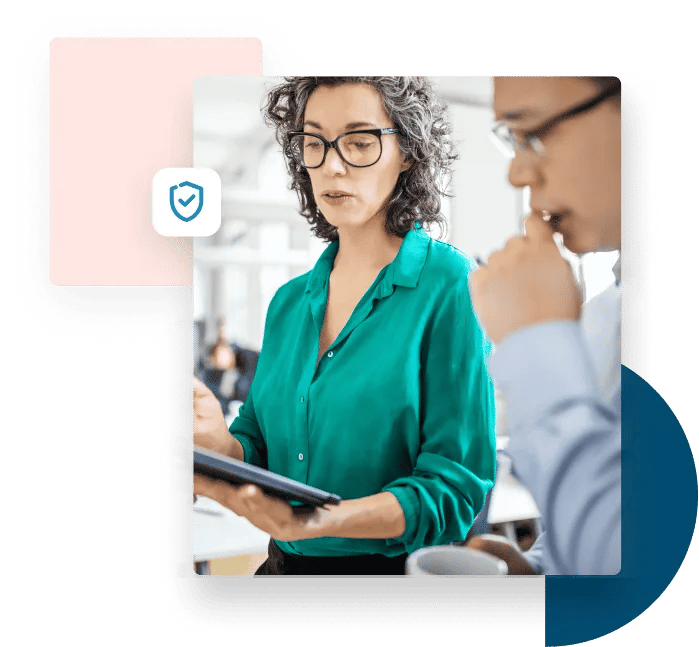 A man in blue and a woman in a green blouse look intently at a tablet.