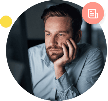 A defeated-looking man holds his head in his hand while illuminated by his computer monitor light.