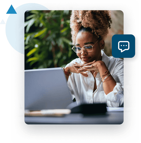 A black woman with glasses sits with her hands crossed under her chin looking at her laptop.