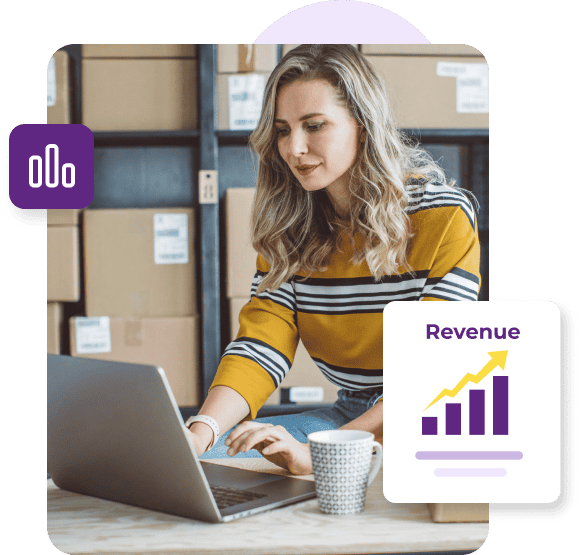 A woman in a yellow sweater with black and white stripes sits in front of a laptop next to a shelf of boxes with a revenue graph showing upward projection.