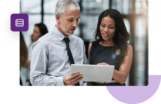 A business man and woman stand shoulder to shoulder while discussing what they're seeing on a tablet.