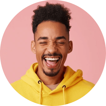 A man in a yellow hooded sweatshirt smiles wide with his eyes closed.