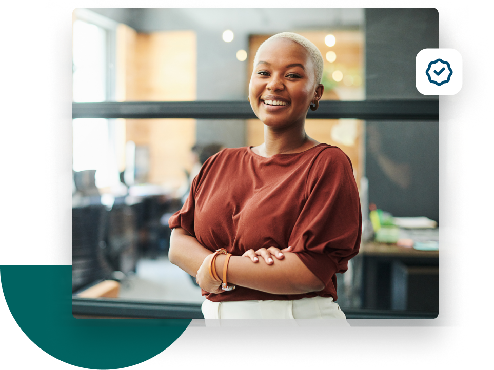 Woman with her arms crossed smiling at the camera from her office