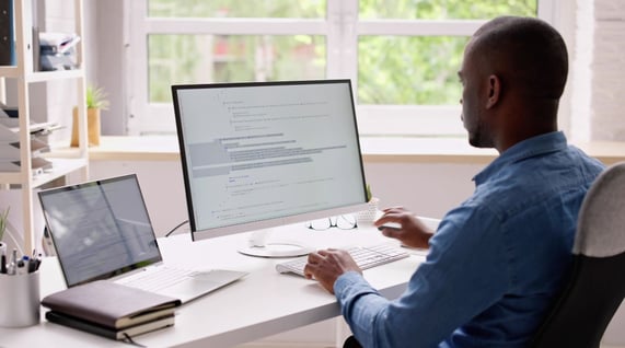 man looks at computer to learn about the average email bounce rate benchmark, reduce bounces and improve email deliverability, with tree behind a window