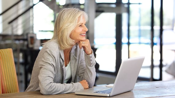 A senior mom sits in front of a laptop after reading an email from one of her children.