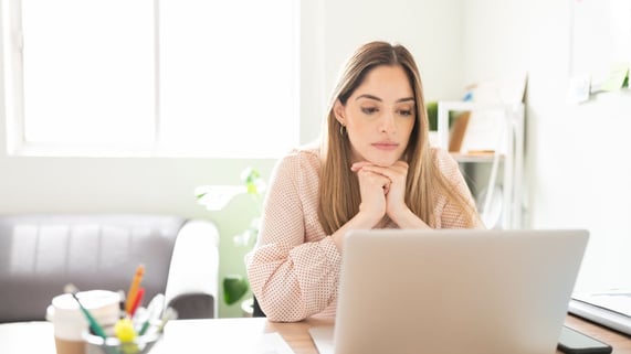 Young woman ponders what to say in cold email to hiring mananger.