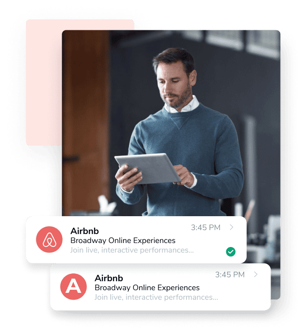 A man in a blue sweater types on a silver tablet next to two emails: one just has an A for a logo, and the other has the AirBnB logo thanks to BIMI.