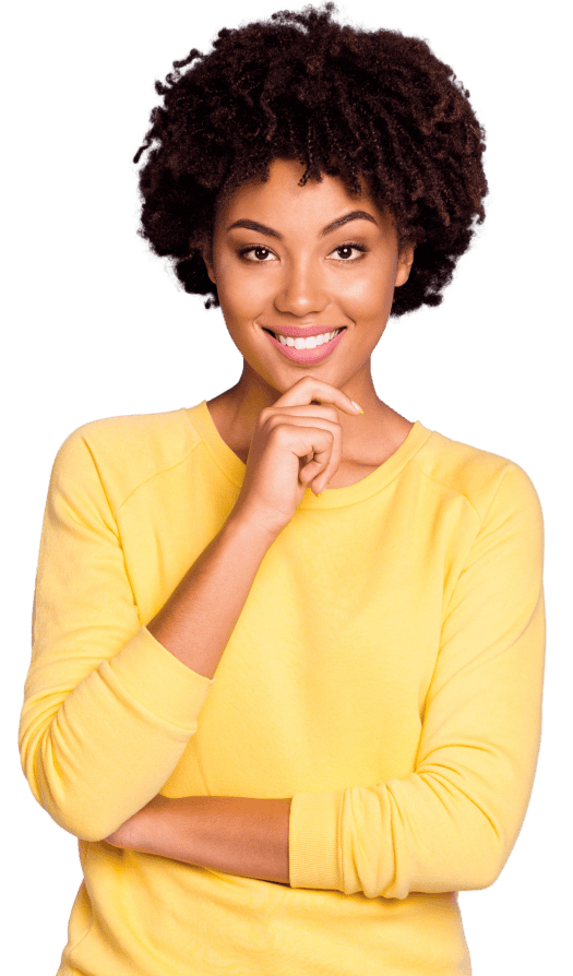 A woman in a yellow long-sleeve holds her hand to her chin and smirks.